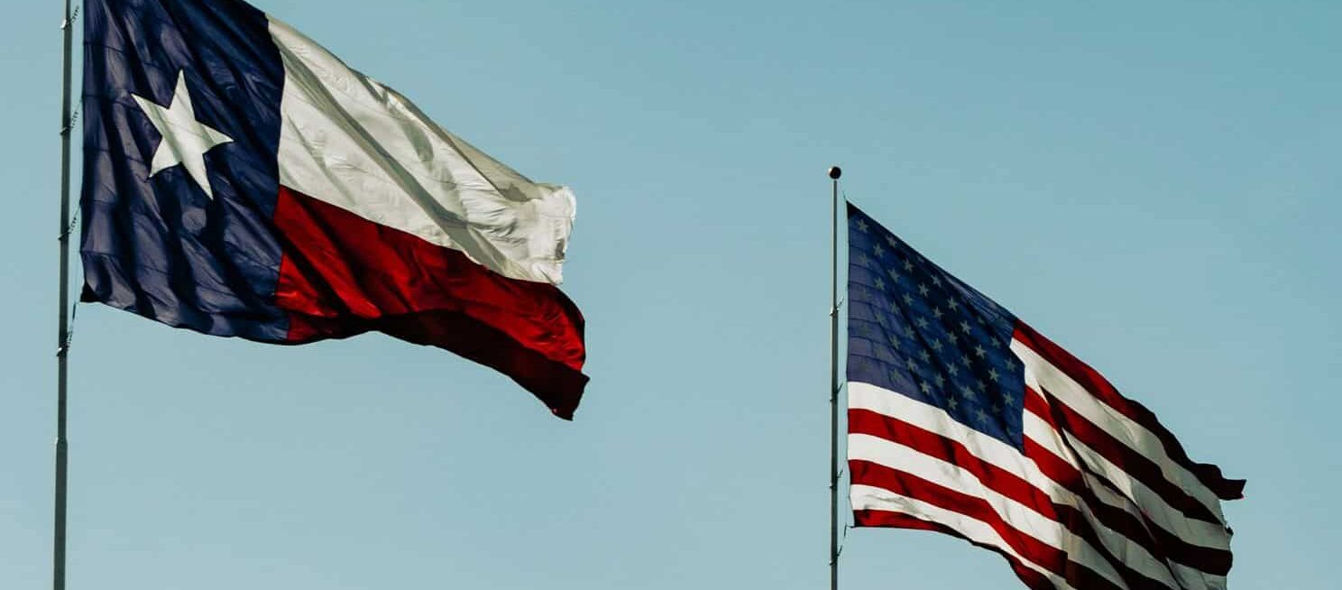 texas flag and american flag in the wind
